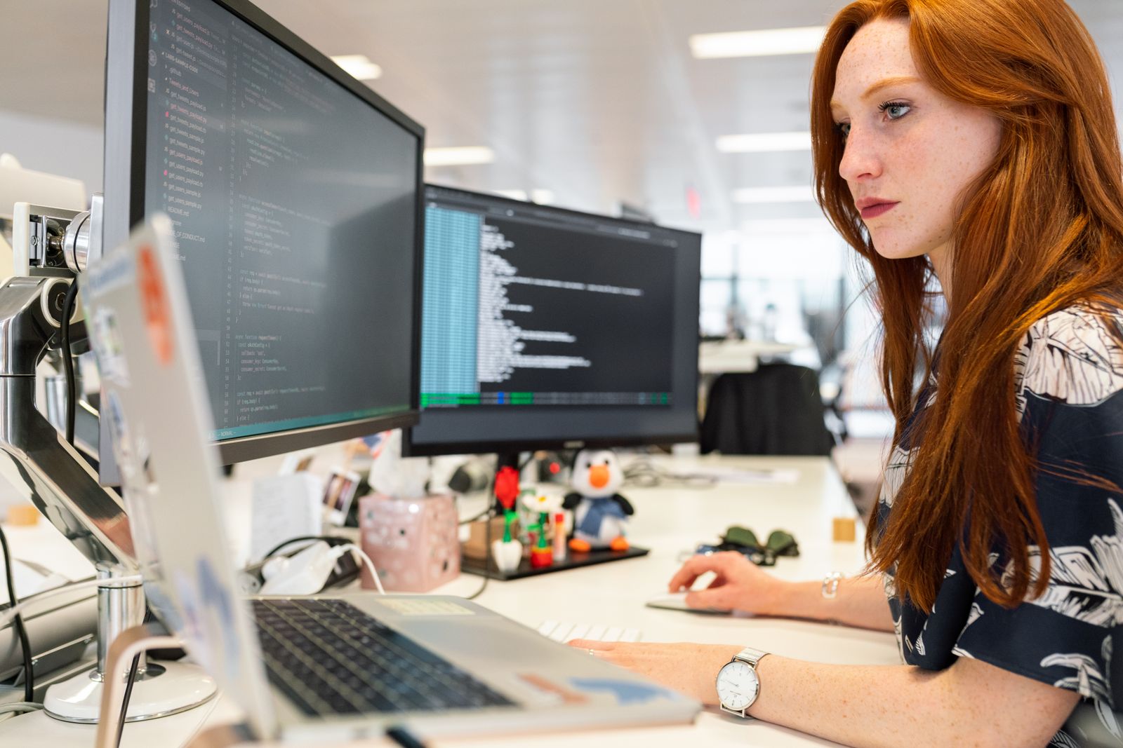 Software engineer reviewing code on multiple monitors